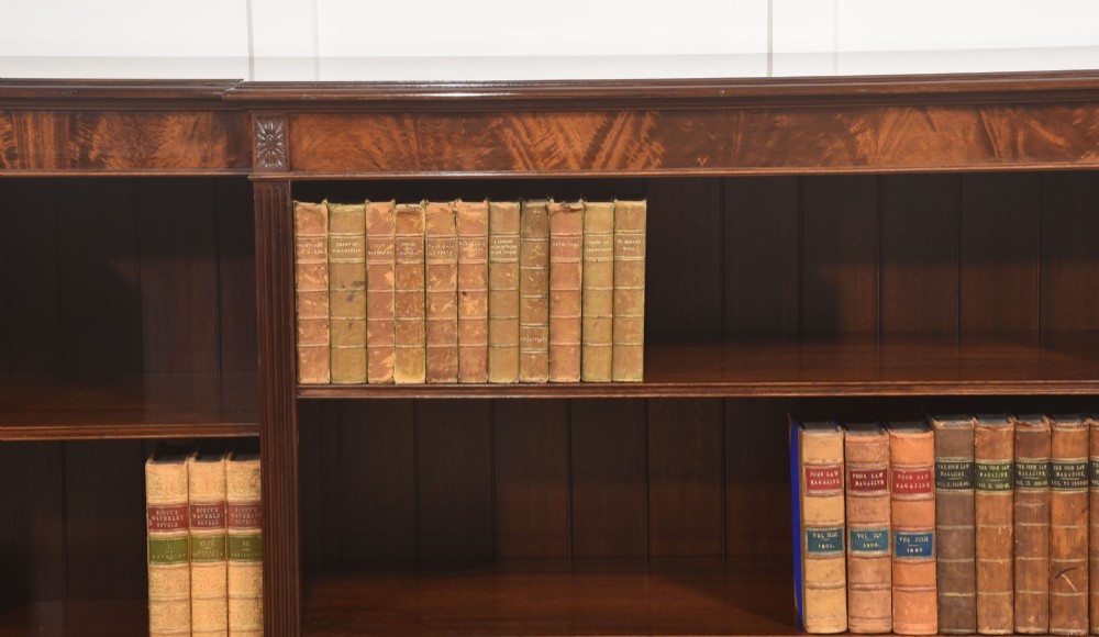 A low flame mahogany breakfront open bookcase featuring fluted pilasters, carved patera rosettes, and three open shelving sections. View II