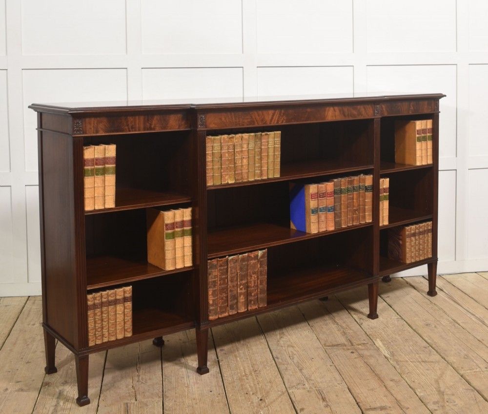 A low flame mahogany breakfront open bookcase featuring fluted pilasters, carved patera rosettes, and three open shelving sections. View IV
