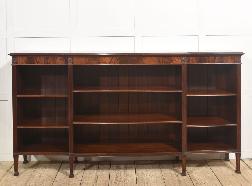 A low flame mahogany breakfront open bookcase featuring fluted pilasters, carved patera rosettes, and three open shelving sections. View VII