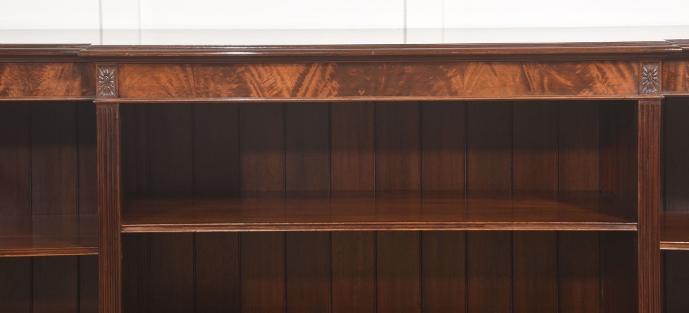 A low flame mahogany breakfront open bookcase featuring fluted pilasters, carved patera rosettes, and three open shelving sections. View VIII