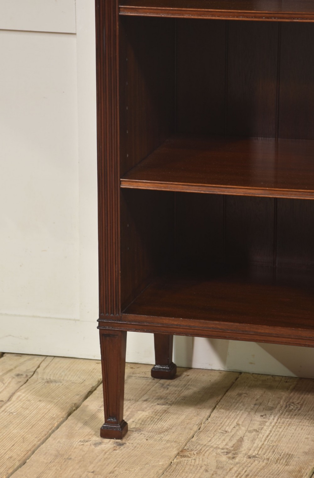 A low flame mahogany breakfront open bookcase featuring fluted pilasters, carved patera rosettes, and three open shelving sections. View IX