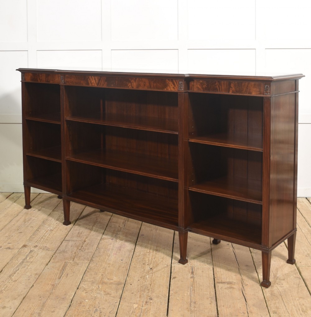A low flame mahogany breakfront open bookcase featuring fluted pilasters, carved patera rosettes, and three open shelving sections. View X