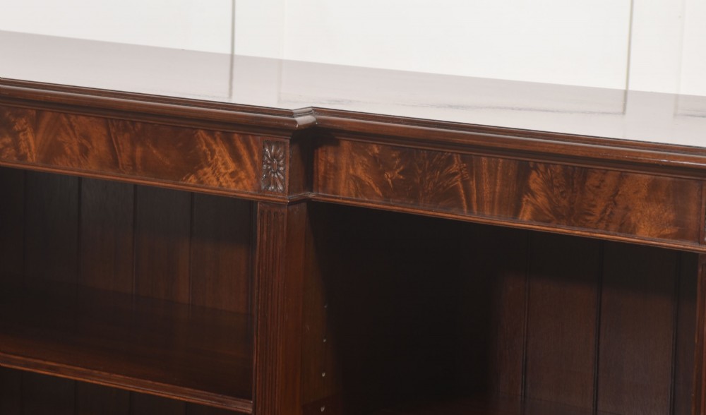 A low flame mahogany breakfront open bookcase featuring fluted pilasters, carved patera rosettes, and three open shelving sections. View XI