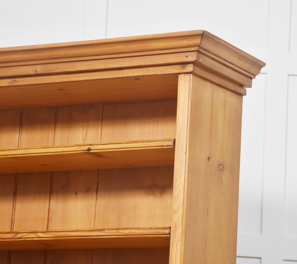 A tall 19th-century pine open bookcase with multiple fixed shelves, a moulded top cornice, planked backboard, and a solid plinth base. View X