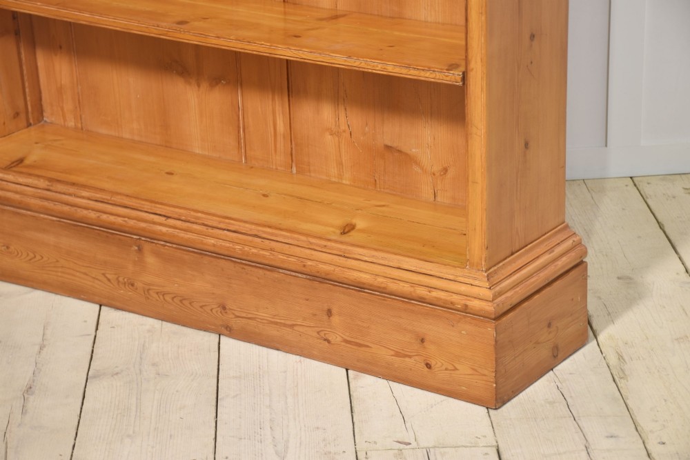 A tall 19th-century pine open bookcase with multiple fixed shelves, a moulded top cornice, planked backboard, and a solid plinth base. View XI