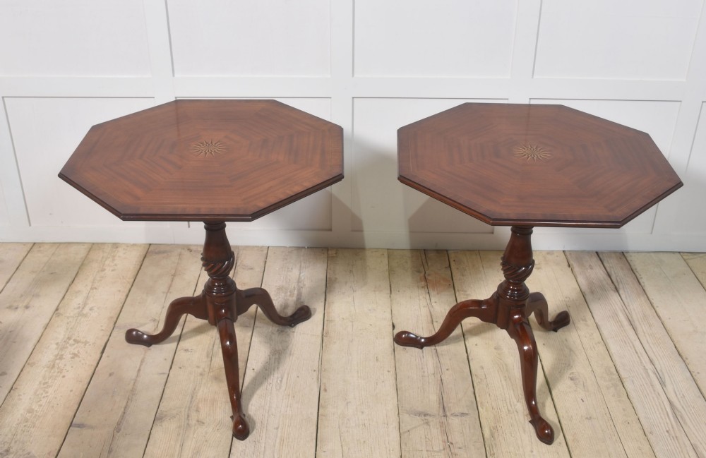 A matching pair of octagonal mahogany tripod tables featuring central starburst marquetry inlays, spiral twist turned columns, and three cabriole legs.