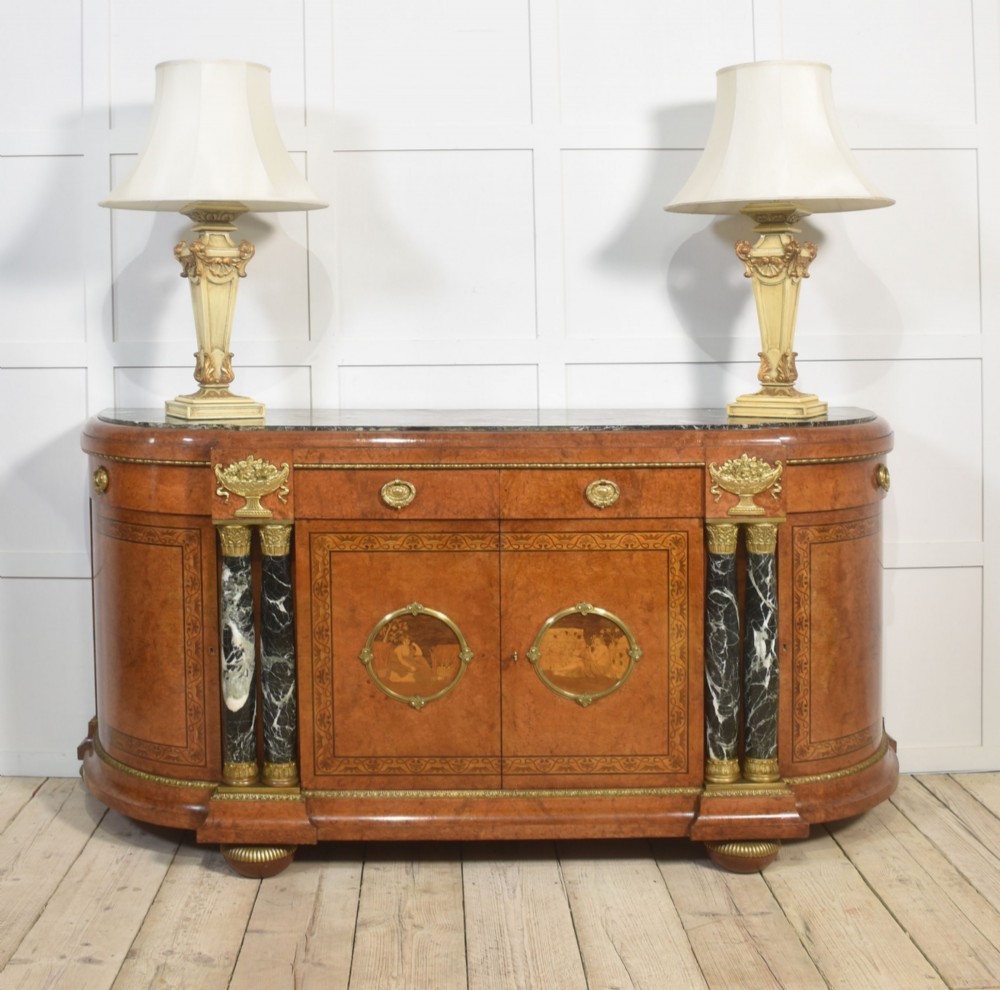 A French bow-front buffet sideboard featuring a dark marble top, burr walnut marquetry, central figural medallions, and flanking marble columns with gilt mounts. View III