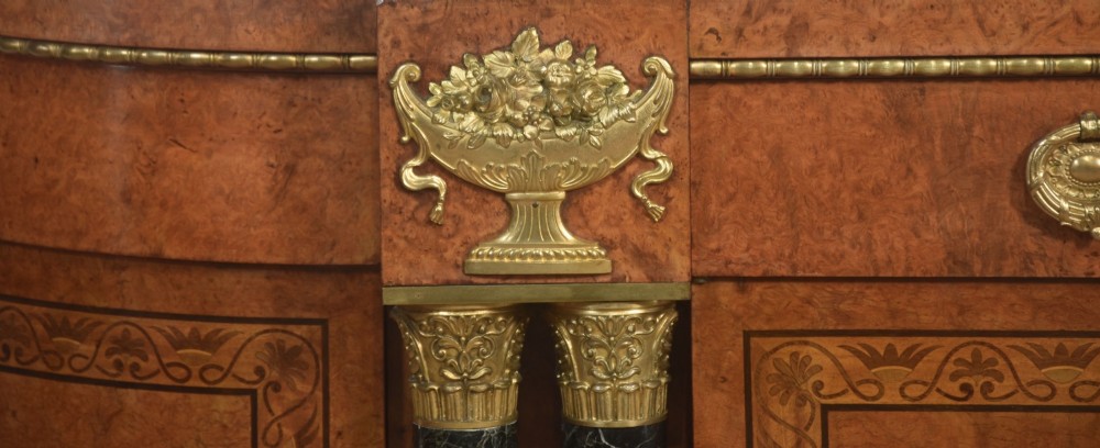 A French bow-front buffet sideboard featuring a dark marble top, burr walnut marquetry, central figural medallions, and flanking marble columns with gilt mounts. View IV