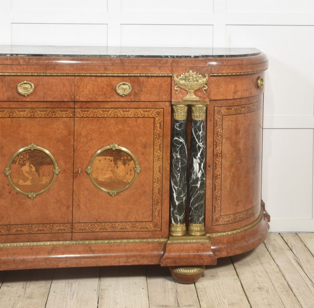 A French bow-front buffet sideboard featuring a dark marble top, burr walnut marquetry, central figural medallions, and flanking marble columns with gilt mounts. View V