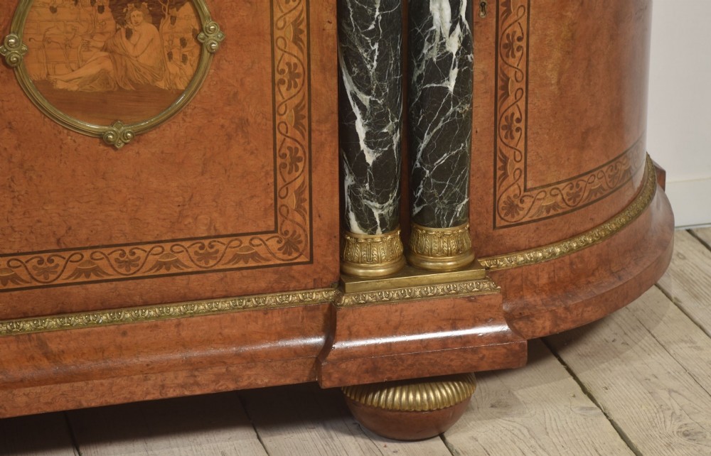 A French bow-front buffet sideboard featuring a dark marble top, burr walnut marquetry, central figural medallions, and flanking marble columns with gilt mounts. View VII