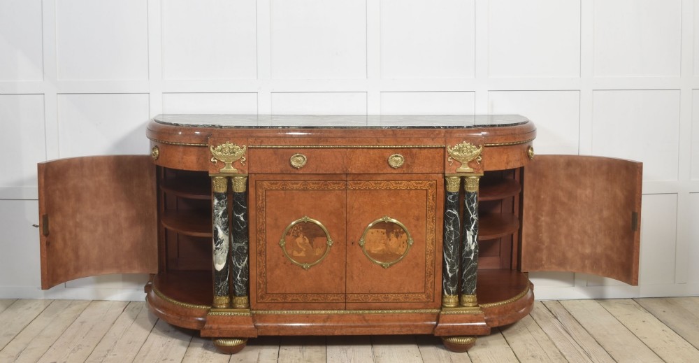 A French bow-front buffet sideboard featuring a dark marble top, burr walnut marquetry, central figural medallions, and flanking marble columns with gilt mounts. View IX