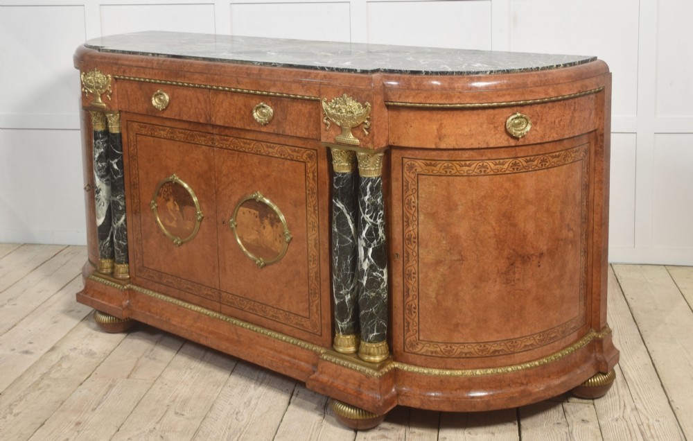 A French bow-front buffet sideboard featuring a dark marble top, burr walnut marquetry, central figural medallions, and flanking marble columns with gilt mounts. View XI