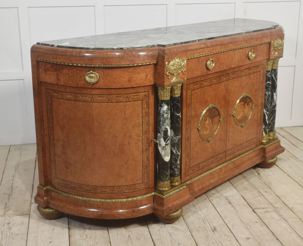 A French bow-front buffet sideboard featuring a dark marble top, burr walnut marquetry, central figural medallions, and flanking marble columns with gilt mounts. View XII