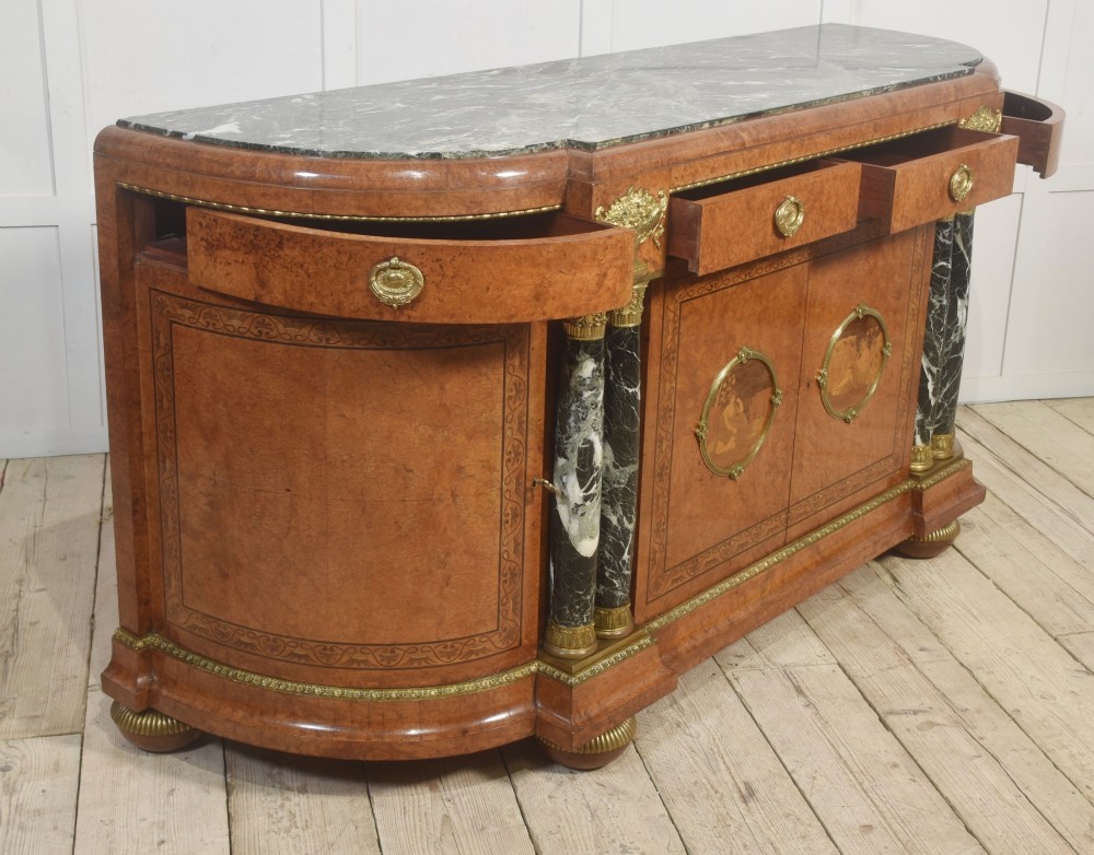 A French bow-front buffet sideboard featuring a dark marble top, burr walnut marquetry, central figural medallions, and flanking marble columns with gilt mounts. View XIV