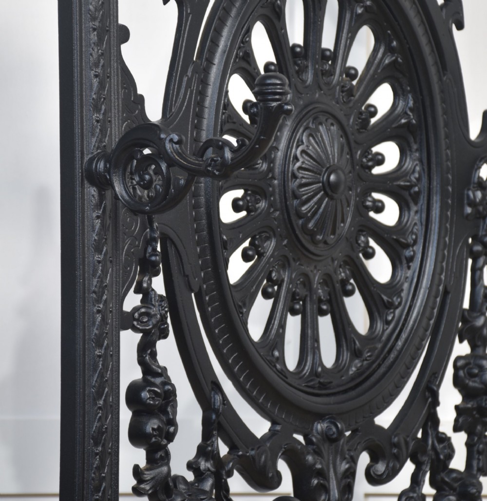 A tall black cast iron hall stand in the Coalbrookdale style featuring intricate scrollwork, coat hooks, an umbrella rail, and a drip tray base. View XI