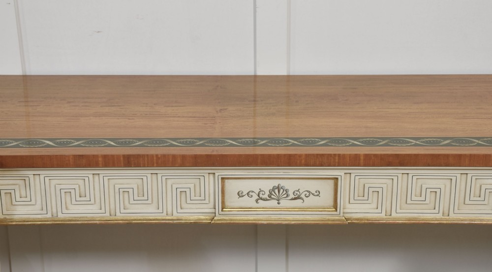 A long Neoclassical style console table featuring a polished timber top with an inlaid border, an off-white apron decorated with a painted Greek key pattern, and carved scroll legs with gilt detailing. View VI