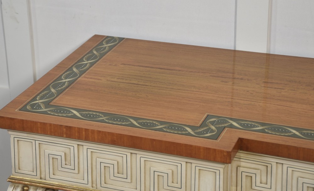 A long Neoclassical style console table featuring a polished timber top with an inlaid border, an off-white apron decorated with a painted Greek key pattern, and carved scroll legs with gilt detailing. View IX