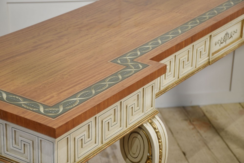 A long Neoclassical style console table featuring a polished timber top with an inlaid border, an off-white apron decorated with a painted Greek key pattern, and carved scroll legs with gilt detailing. View XI