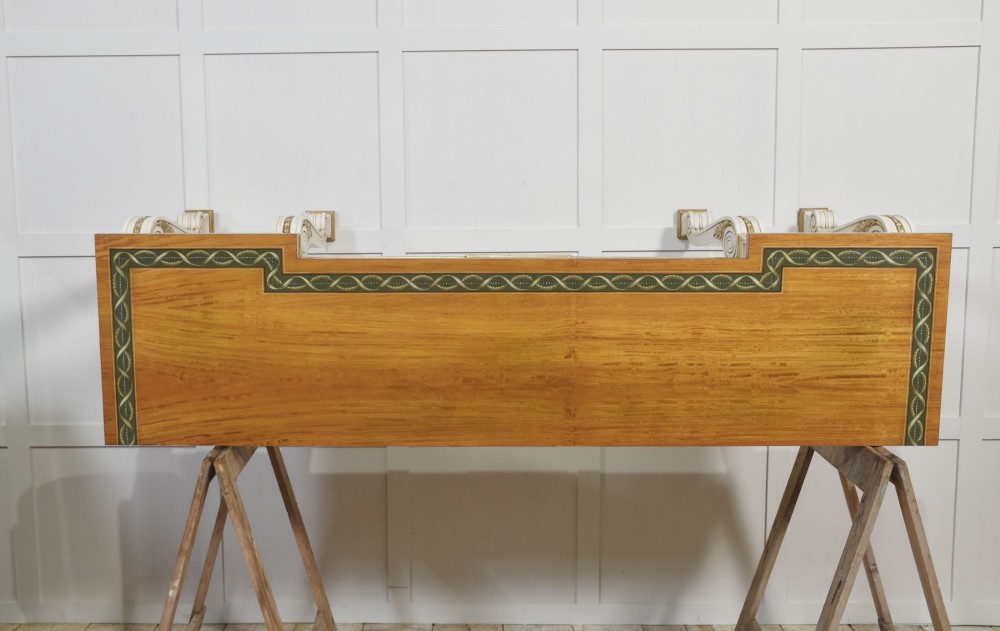 A long Neoclassical style console table featuring a polished timber top with an inlaid border, an off-white apron decorated with a painted Greek key pattern, and carved scroll legs with gilt detailing. View XII