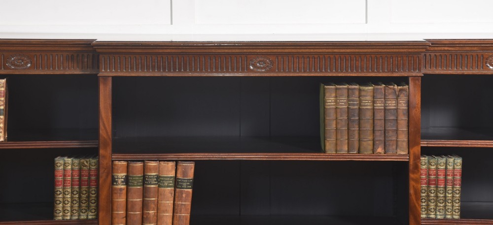 A large mahogany breakfront open library bookcase featuring multiple shelves, a fluted frieze with carved medallions, and sturdy bracket feet. View II