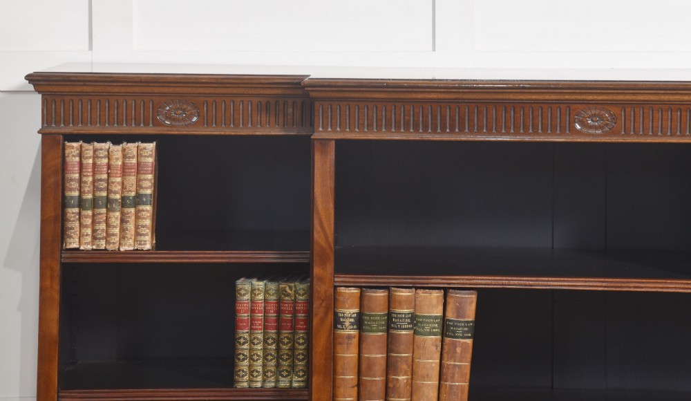A large mahogany breakfront open library bookcase featuring multiple shelves, a fluted frieze with carved medallions, and sturdy bracket feet. View III