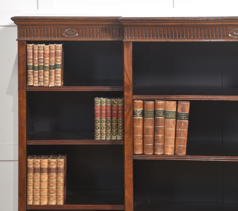A large mahogany breakfront open library bookcase featuring multiple shelves, a fluted frieze with carved medallions, and sturdy bracket feet. View IV