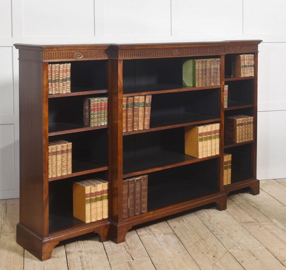 A large mahogany breakfront open library bookcase featuring multiple shelves, a fluted frieze with carved medallions, and sturdy bracket feet. View V