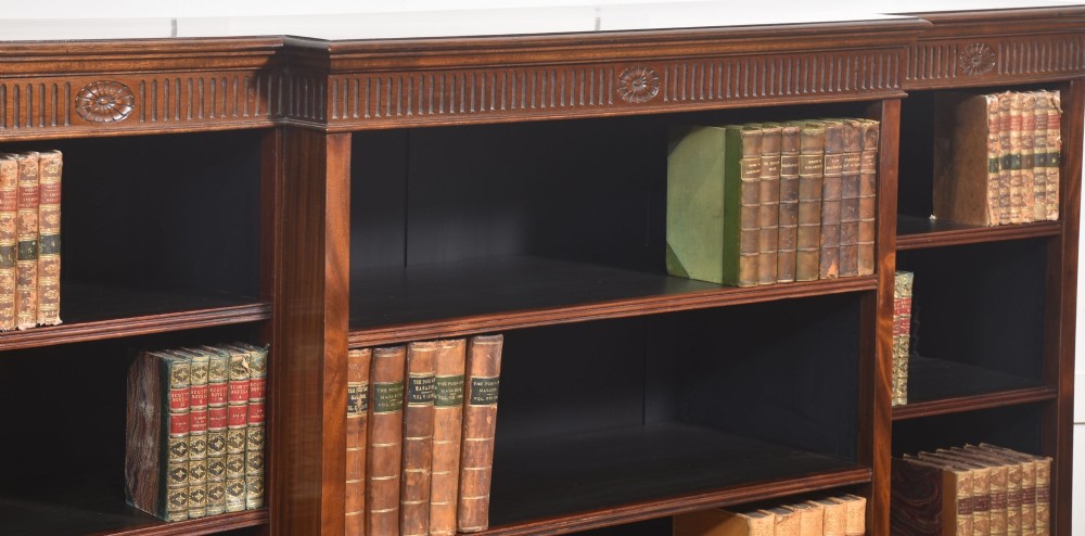 A large mahogany breakfront open library bookcase featuring multiple shelves, a fluted frieze with carved medallions, and sturdy bracket feet. View VI