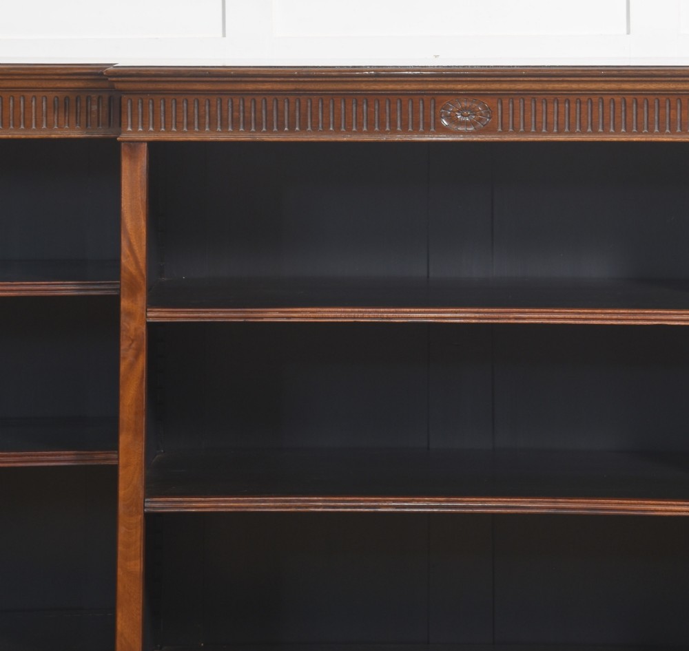 A large mahogany breakfront open library bookcase featuring multiple shelves, a fluted frieze with carved medallions, and sturdy bracket feet. View X