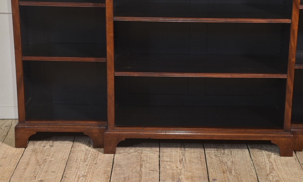 A large mahogany breakfront open library bookcase featuring multiple shelves, a fluted frieze with carved medallions, and sturdy bracket feet. View XI