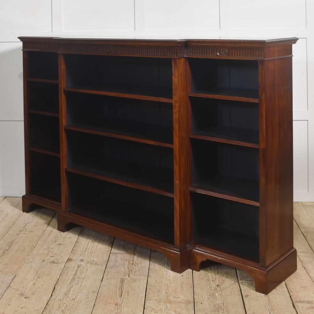 A large mahogany breakfront open library bookcase featuring multiple shelves, a fluted frieze with carved medallions, and sturdy bracket feet. View XII