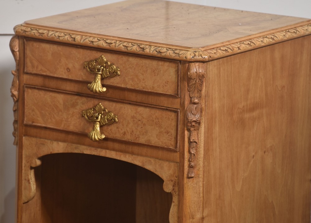 A pair of golden burr walnut bedside cabinets featuring two upper drawers with brass drop handles above an open cubby, set on carved cabriole legs with claw and ball feet. View III