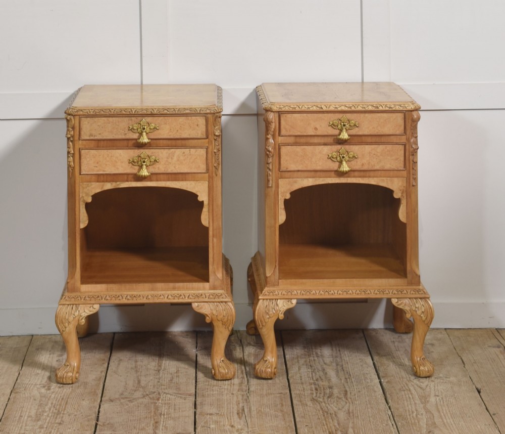 A pair of golden burr walnut bedside cabinets featuring two upper drawers with brass drop handles above an open cubby, set on carved cabriole legs with claw and ball feet. View VI