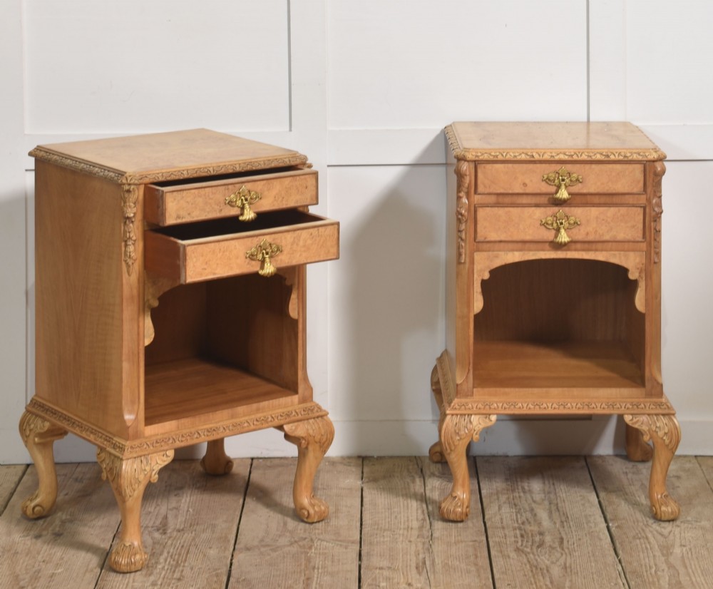 A pair of golden burr walnut bedside cabinets featuring two upper drawers with brass drop handles above an open cubby, set on carved cabriole legs with claw and ball feet. View VII