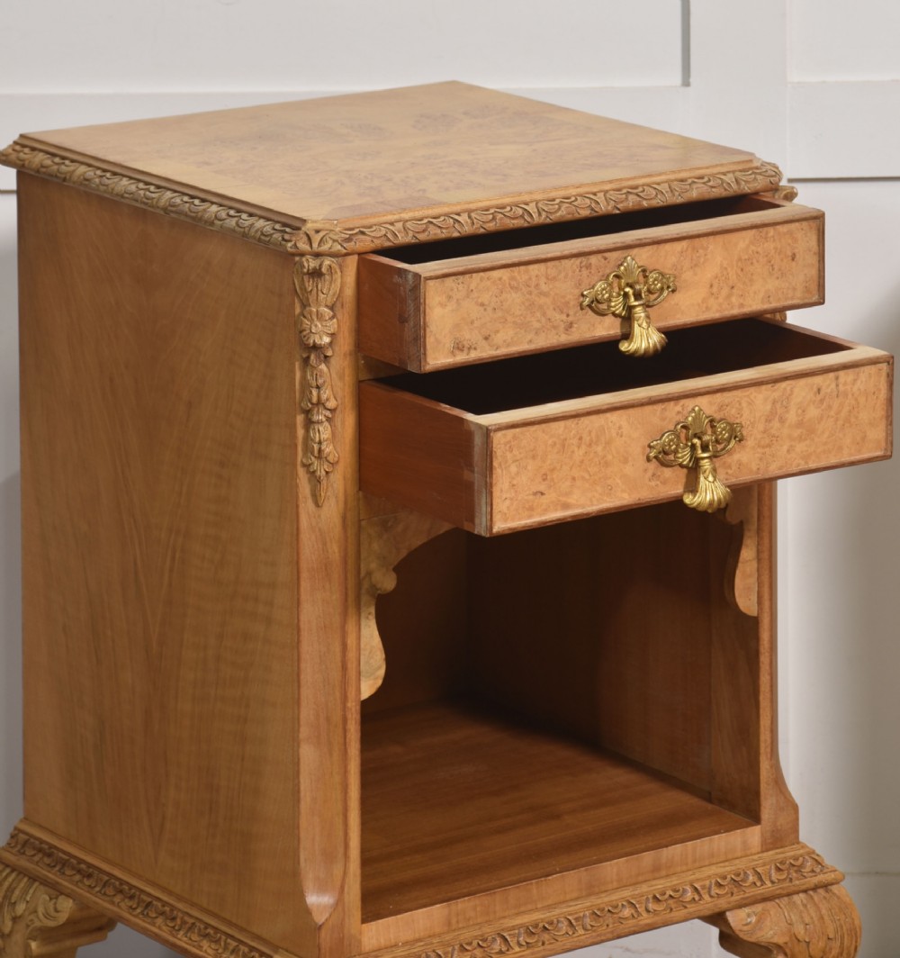 A pair of golden burr walnut bedside cabinets featuring two upper drawers with brass drop handles above an open cubby, set on carved cabriole legs with claw and ball feet. View VIII