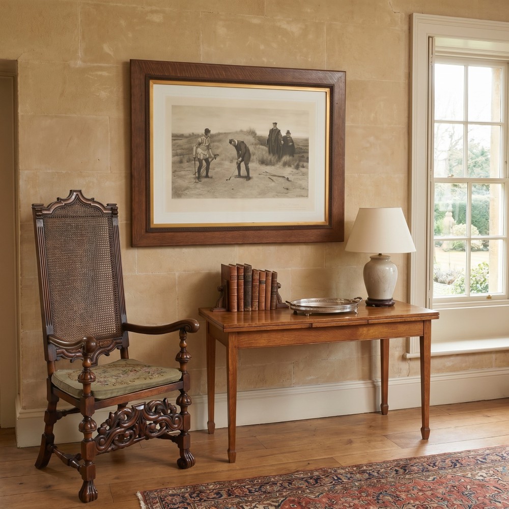 A large monochrome Victorian narrative print depicting golf players on coastal dunes being observed by clergymen, framed in quarter-sawn oak with a gilt inner slip. View II