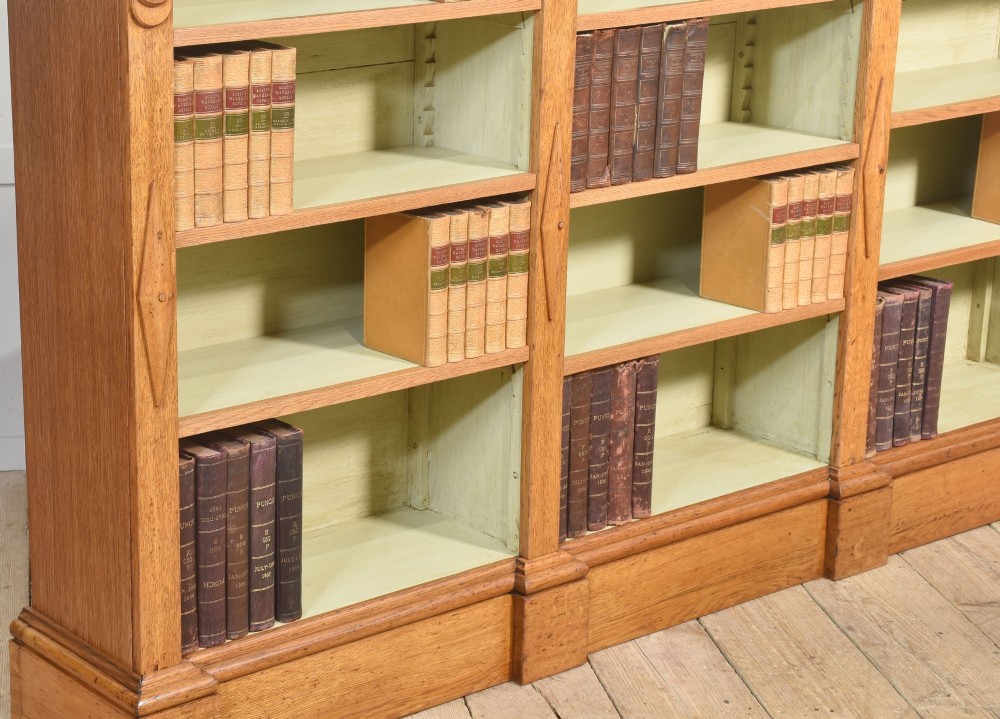 A large 19th-century oak open bookcase featuring three bays, carved decorative corbels, adjustable shelves, and a pale green painted interior. View III