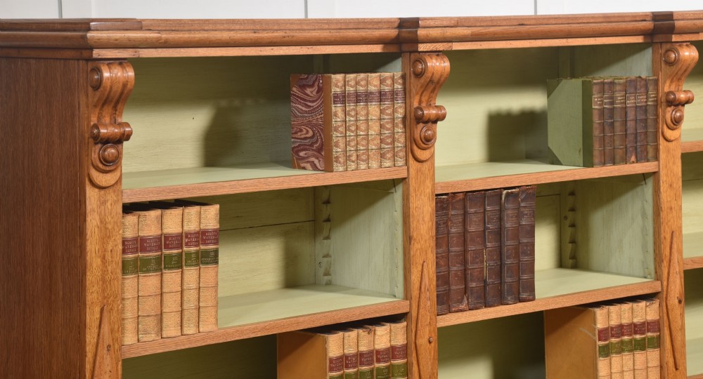 A large 19th-century oak open bookcase featuring three bays, carved decorative corbels, adjustable shelves, and a pale green painted interior. View IV