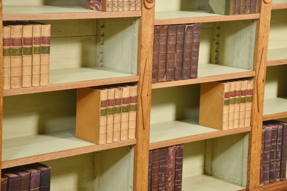 A large 19th-century oak open bookcase featuring three bays, carved decorative corbels, adjustable shelves, and a pale green painted interior. View V
