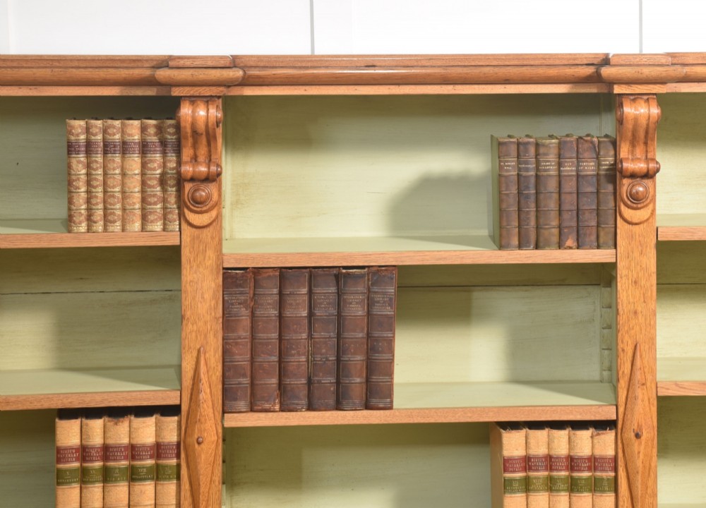 A large 19th-century oak open bookcase featuring three bays, carved decorative corbels, adjustable shelves, and a pale green painted interior. View XI