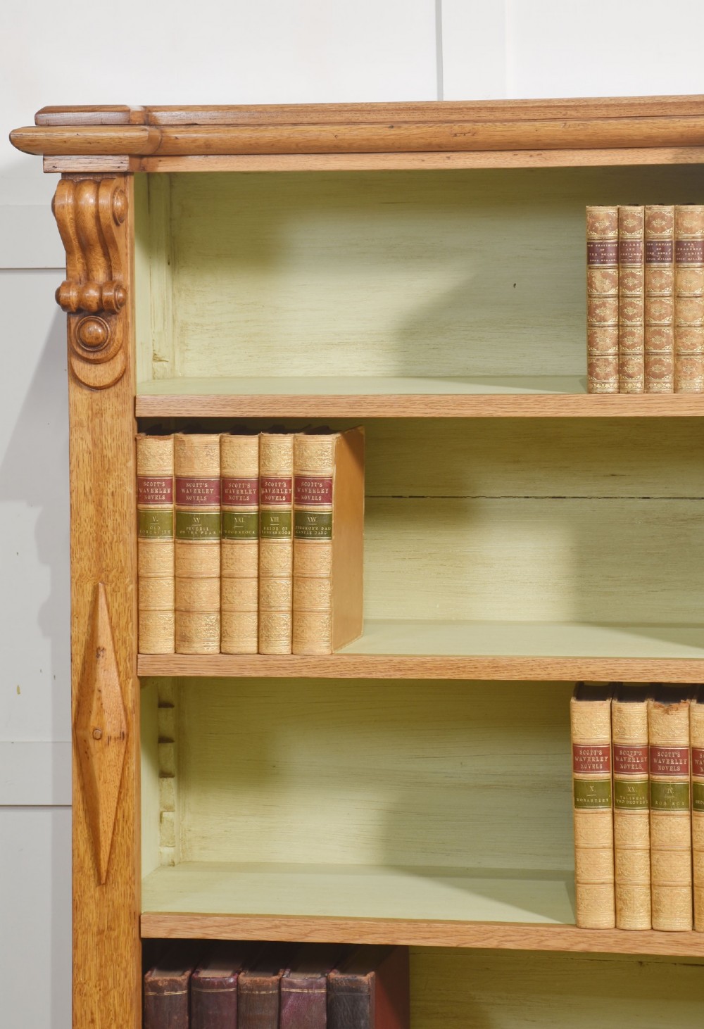 A large 19th-century oak open bookcase featuring three bays, carved decorative corbels, adjustable shelves, and a pale green painted interior. View XII
