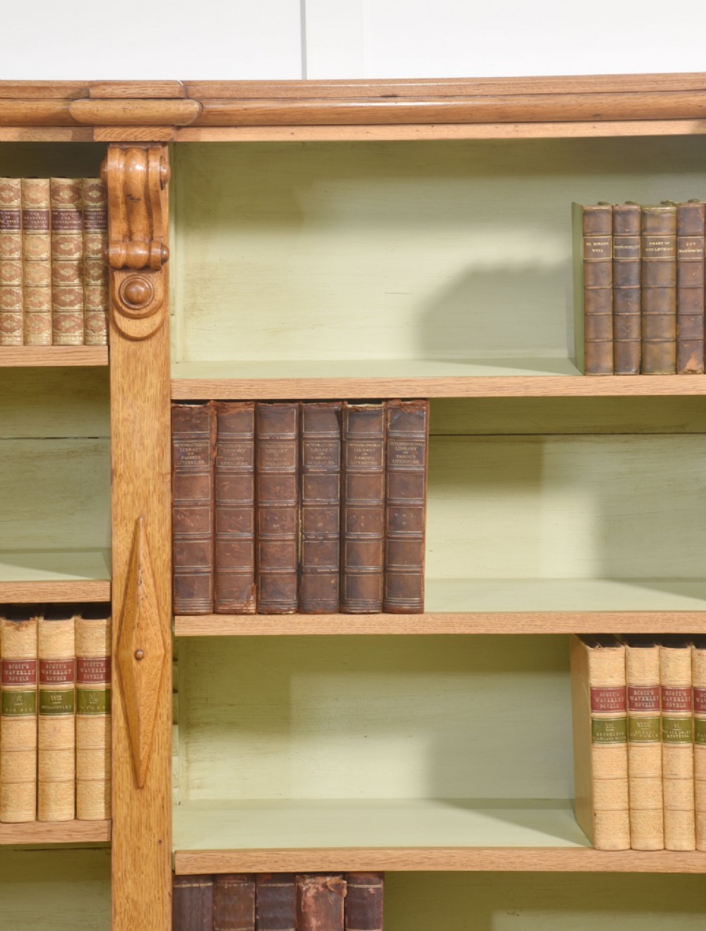 A large 19th-century oak open bookcase featuring three bays, carved decorative corbels, adjustable shelves, and a pale green painted interior. View XIII