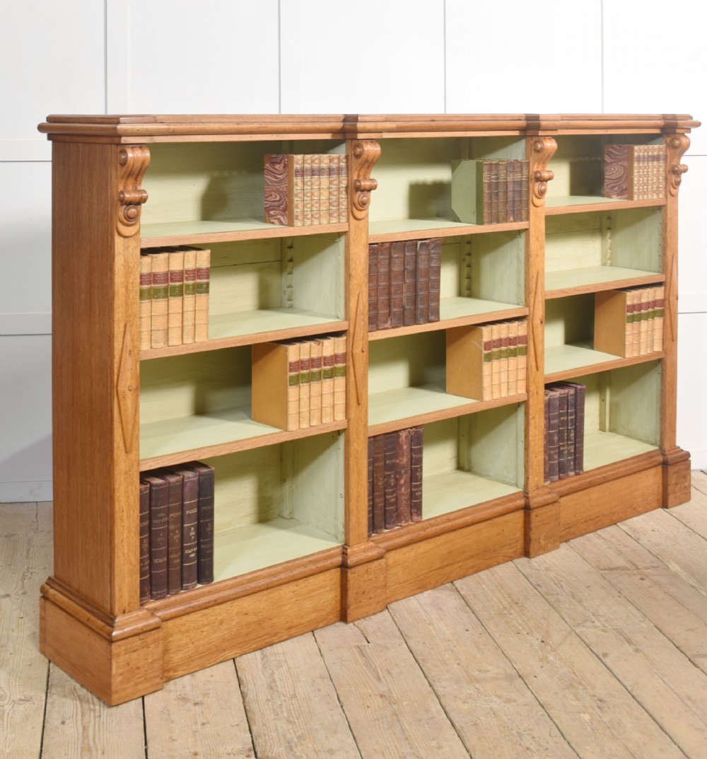 A large 19th-century oak open bookcase featuring three bays, carved decorative corbels, adjustable shelves, and a pale green painted interior. View XIV