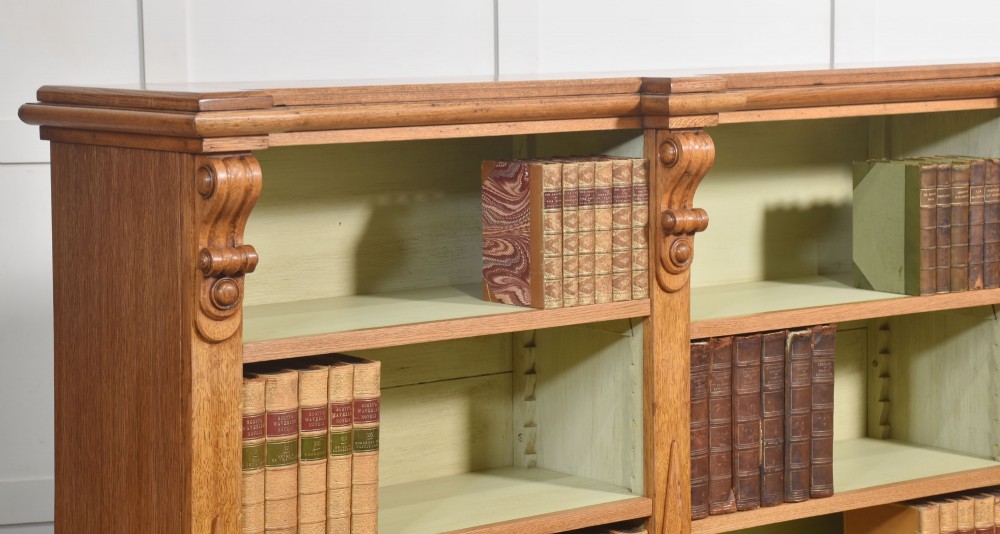 A large 19th-century oak open bookcase featuring three bays, carved decorative corbels, adjustable shelves, and a pale green painted interior. View XV