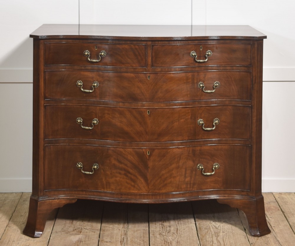 An Edwardian figured mahogany bow front chest of drawers featuring two short over three long drawers with brass swan-neck handles and splayed bracket feet.