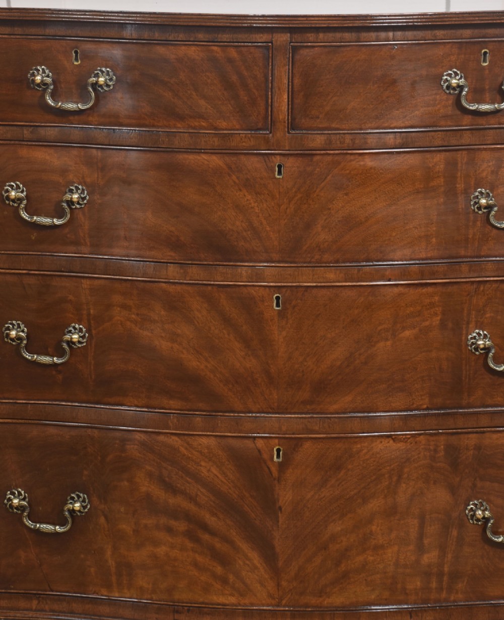 An Edwardian figured mahogany bow front chest of drawers featuring two short over three long drawers with brass swan-neck handles and splayed bracket feet. View III