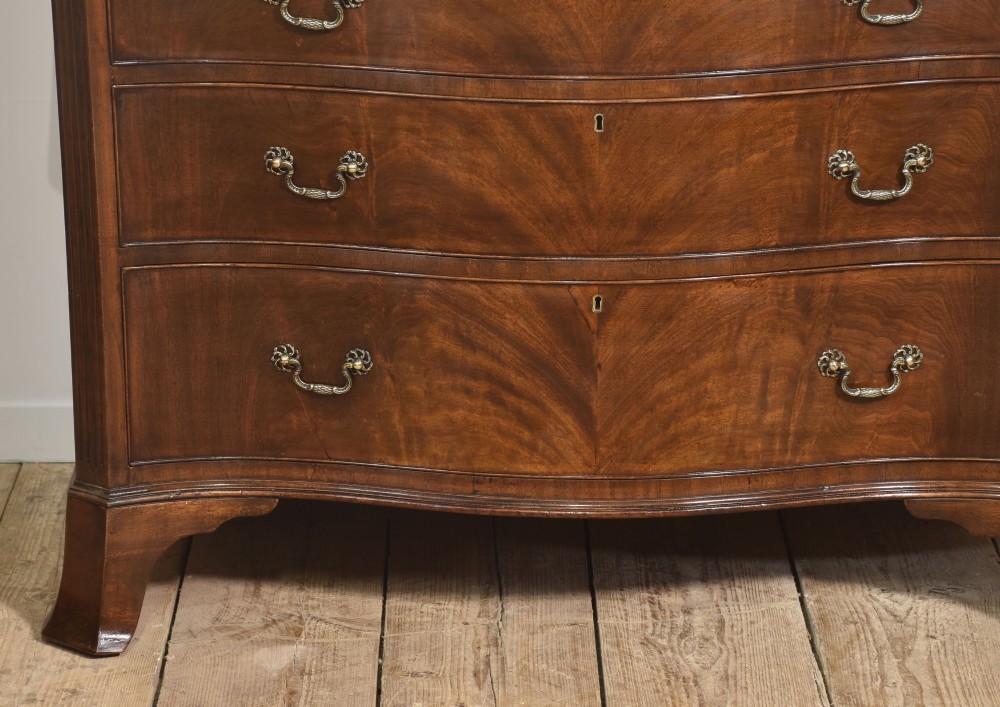 An Edwardian figured mahogany bow front chest of drawers featuring two short over three long drawers with brass swan-neck handles and splayed bracket feet. View IV