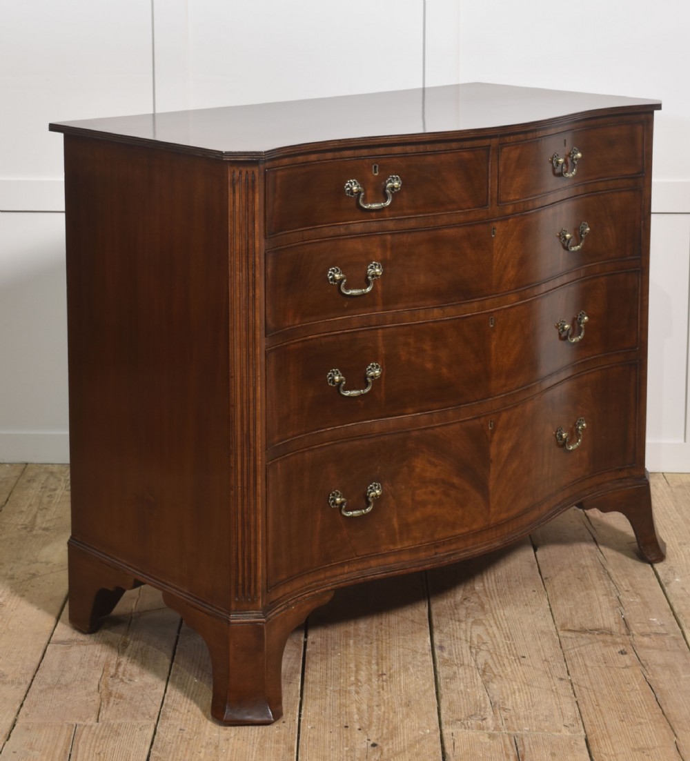 An Edwardian figured mahogany bow front chest of drawers featuring two short over three long drawers with brass swan-neck handles and splayed bracket feet. View V