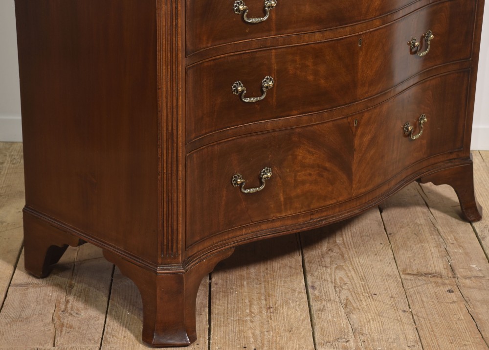 An Edwardian figured mahogany bow front chest of drawers featuring two short over three long drawers with brass swan-neck handles and splayed bracket feet. View VI