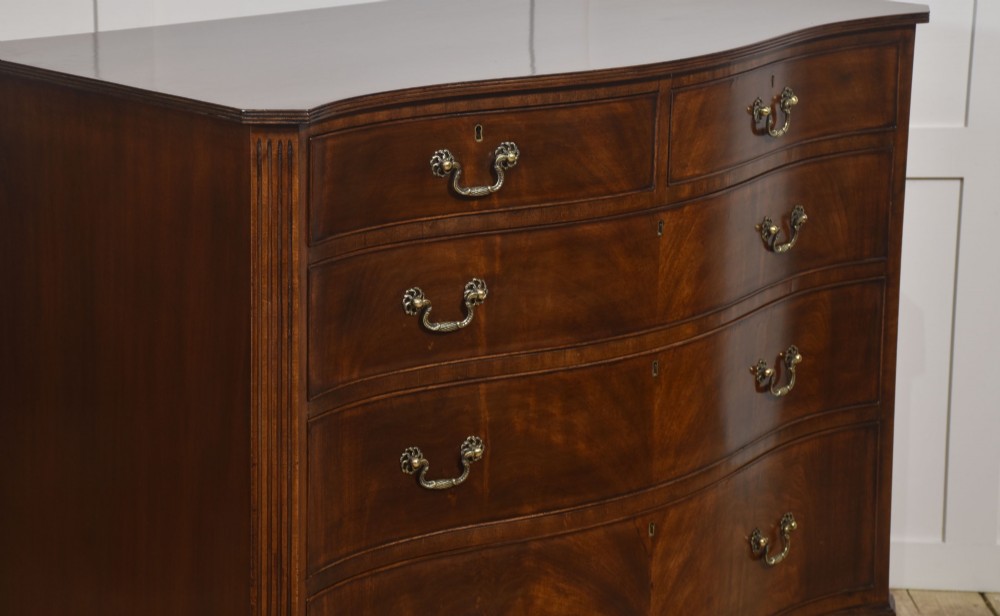An Edwardian figured mahogany bow front chest of drawers featuring two short over three long drawers with brass swan-neck handles and splayed bracket feet. View VII